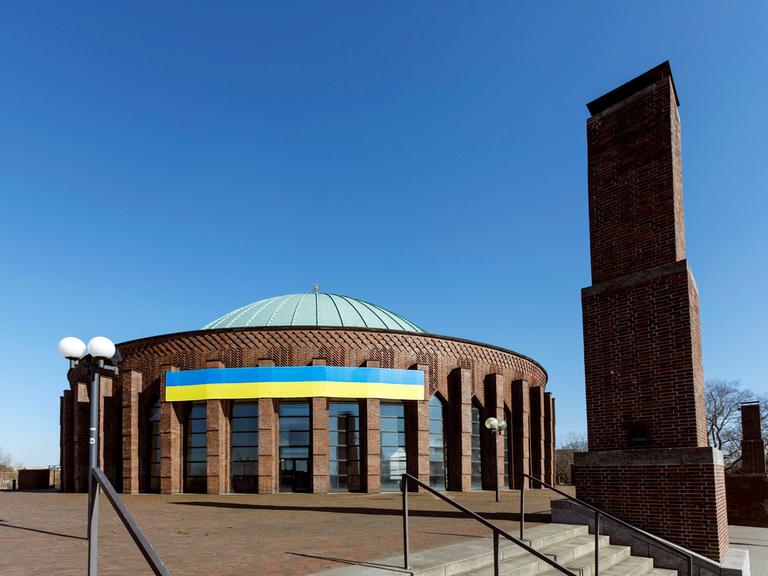 Die blau-gelbe Nationalfahne der Ukraine in an der runden Tonhalle Düsseldorf gespannt und damit weit sichtbar.