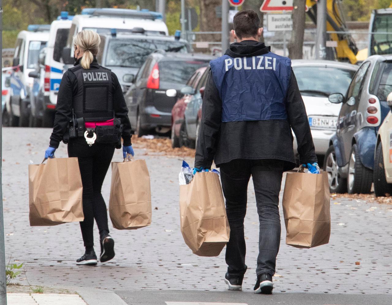 Durchsuchungen in einer Wohnung des Remmo-Clan in Neukölln. Polizeimitarbeitende tragen Beweismittel in braunen Tüten über die Strasse.