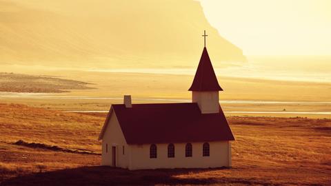 Eine abgeschiedene Kirche am Strand bei Sonnenuntergang.