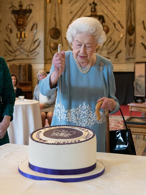 Torte zum 70. Thronjubliäum: Elisabeth II. am 5. Februar 2022 in der königlichen Residenz in Norfolk:Torte zum Thronjubliäum : Die britische Königin Elisabeth II. schneidet am 5. F-ebruar 2022 in Sandringham House. der königlichen Residenz in Norfolk ein Festagstorte an
