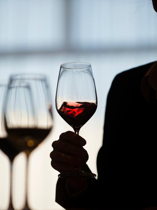 Eine Teilnehmerin schwenkt während einer Weinverkostung einen Rotwein im Glas. Foto: Gregor Fischer/dpa ++