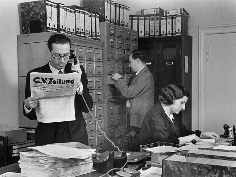 Hans Oppenheimer (im Vordergrund) mit zwei weiteren Mitarbeitenden in der Redaktion der C.V.-Zeitung