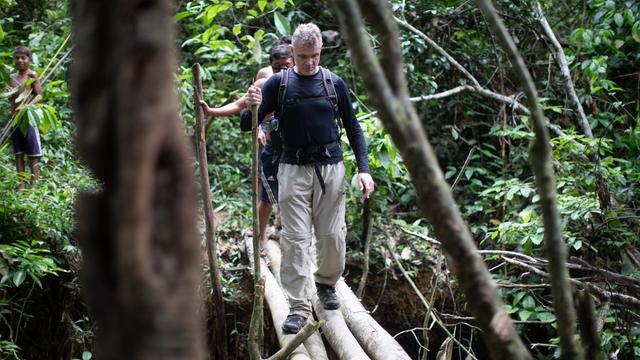 Der Journalist Dom Phillips läuft mit zwei Indigenen über Baumstämme im Amazonasgebiet.