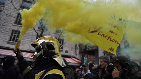 Feuerwehrleute ziehen aus Protest gegen den Staat mit Fahnen und Rauchwolken durch die Straßen von Paris.