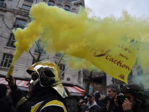 Feuerwehrleute ziehen aus Protest gegen den Staat mit Fahnen und Rauchwolken durch die Straßen von Paris.