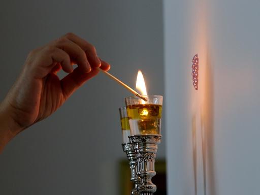 Eine Frau zündet Shabbat-Kerzen an.