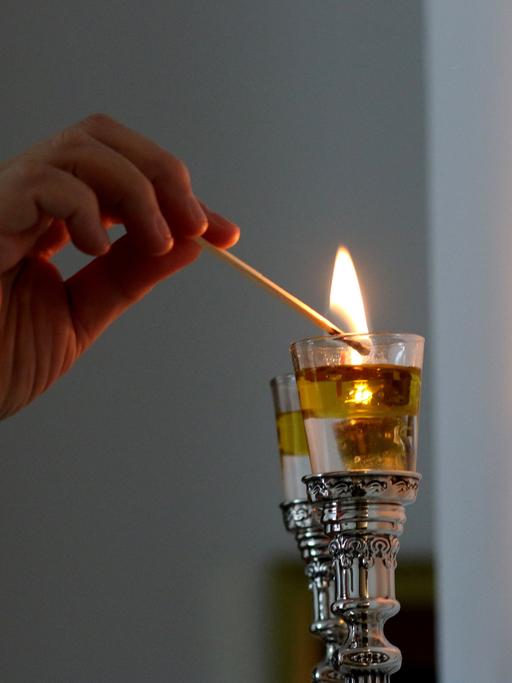 Eine Frau zündet Shabbat-Kerzen an.