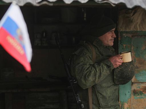 Separatisten der Volksrepublik Luhansk am 9. Dezember 2021.  Ein Offizier der separatistischen Volksrepublik Luhansk steht mit geschultertem Gewehr und einem Teepott in der Hand in einem Unterstand in der Nähe von Slawjanoserbsk in der Ostukraine an der Kontaktlinie zwischen den ukrainischen Regierungstruppen und den separatistischen Kräften der Volksrepublik Luhansk.
