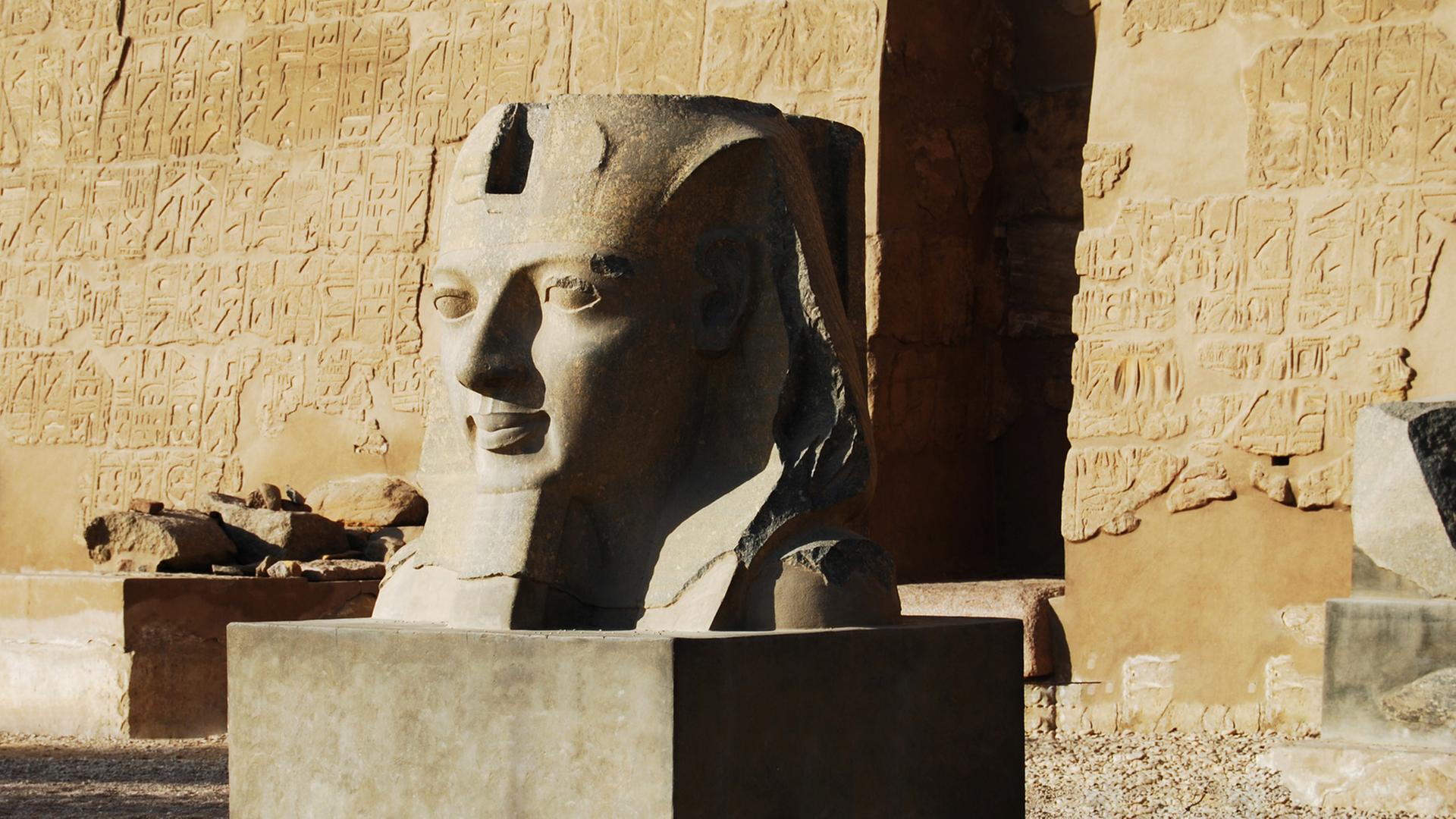 Schon bei ihrer Ankunft in Luxor werden Prof. van Dusen und sein Begleiter vor dem Fluch des Pharao gewarnt. Zu sehen: Eine Pharo-Skulptur vor einer sandfarbenen Wand in Luxor Schon bei ihrer Ankunft in Luxor werden Prof. van Dusen und sein Begleiter vor dem Fluch des Pharao gewarnt. Zu sehen: Eine Pharo-Skulptur vor einer sandfarbenen Wand in Luxor