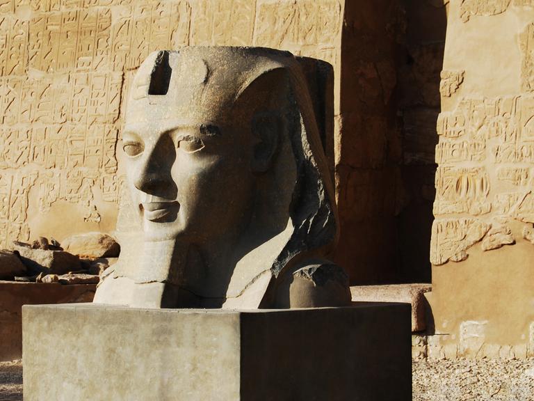Schon bei ihrer Ankunft in Luxor werden Prof. van Dusen und sein Begleiter vor dem Fluch des Pharao gewarnt. Zu sehen: Eine Pharo-Skulptur vor einer sandfarbenen Wand in Luxor