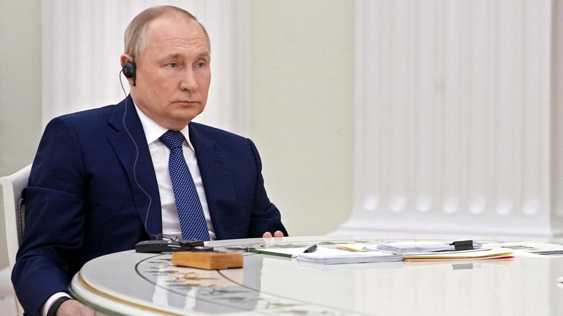 Wladimir Putin sitzt an einem Tisch und hört zu. Wladimir Putin sitzt an einem Tisch und hört zu.