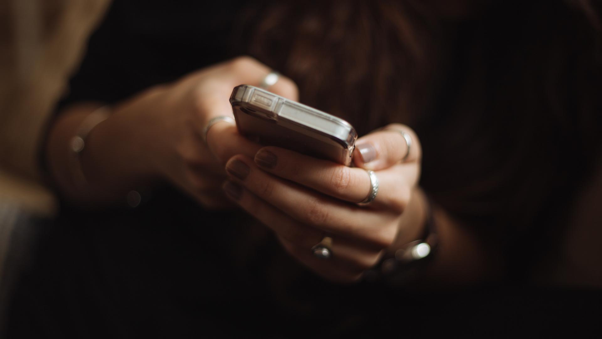Eine Person hält ein Smartphone mit beiden Händen. Eine Person hält ein Smartphone mit beiden Händen.