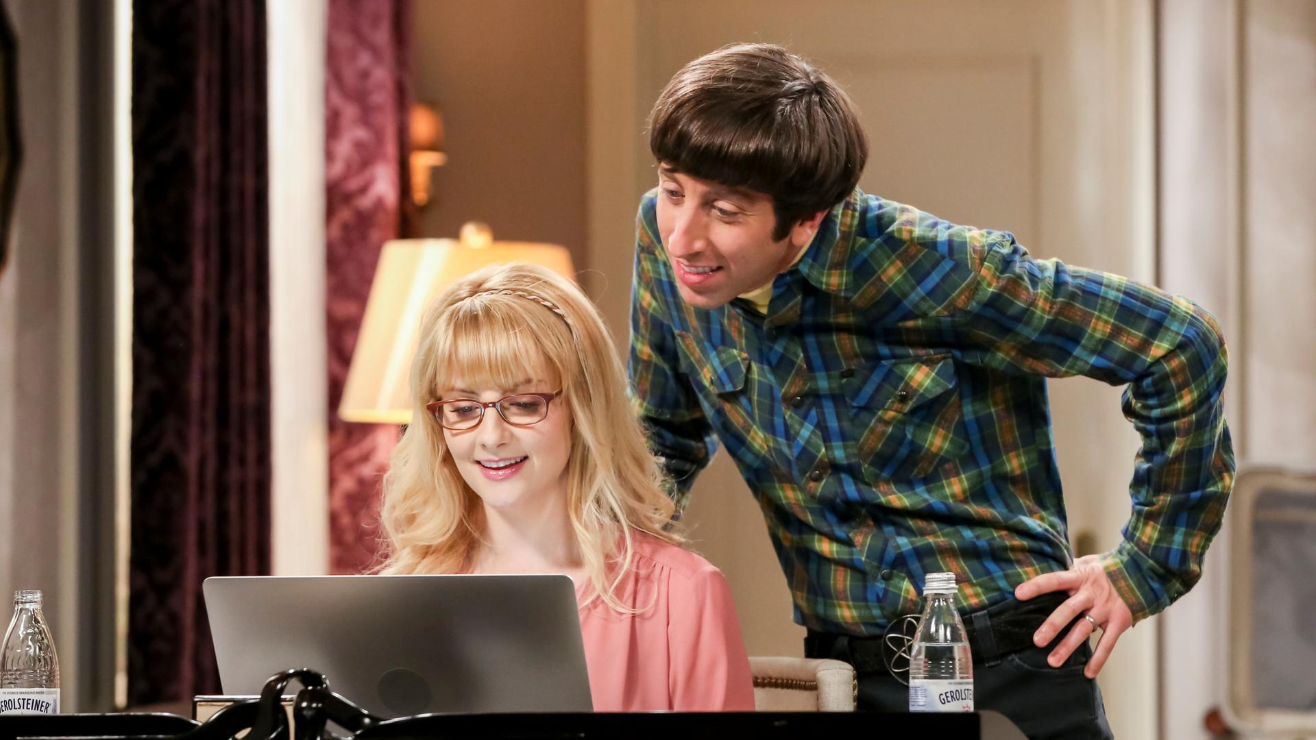 Ein Szenenfoto aus der US-TV-Serie "The Big Bang Theory". Es zeigt die Schauspielerin Melissa Rauch und den Schauspieler Simon Helberg. Sie sitzt am Laptop, er steht schräg hinter ihr. Ein Szenenfoto aus der US-TV-Serie "The Big Bang Theory". Es zeigt die Schauspielerin Melissa Rauch und den Schauspieler Simon Helberg. Sie sitzt am Laptop, er steht schräg hinter ihr.