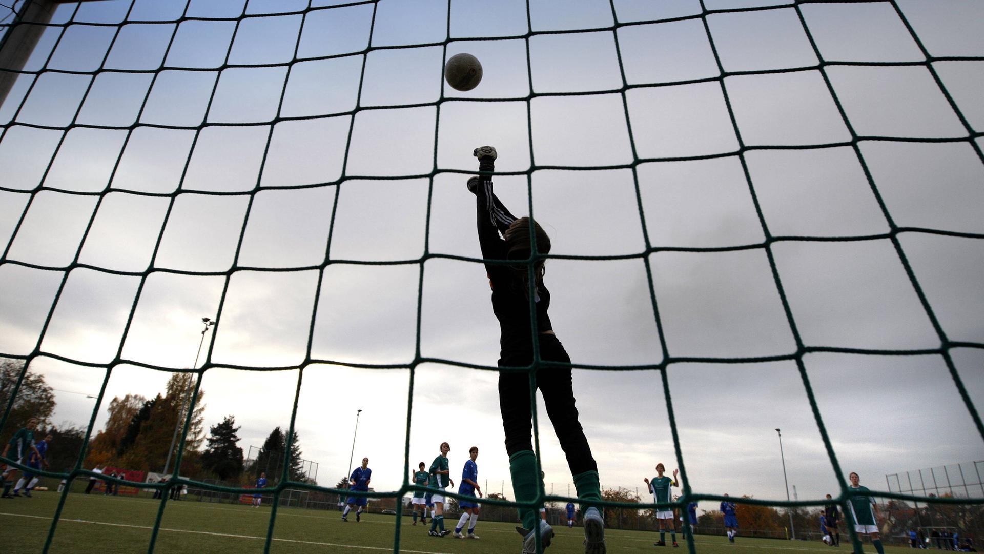 Eine Torhüterin wehrt einen Ball ab. Eine Torhüterin wehrt einen Ball ab.