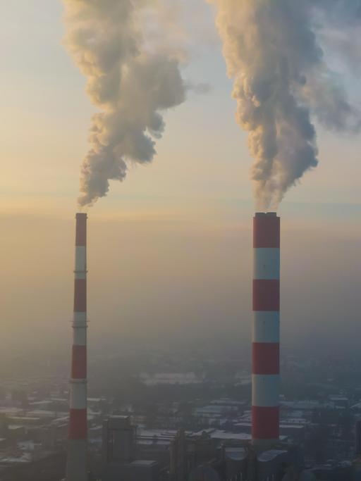 Blick auf zwei rauchende Industrieschornsteine 