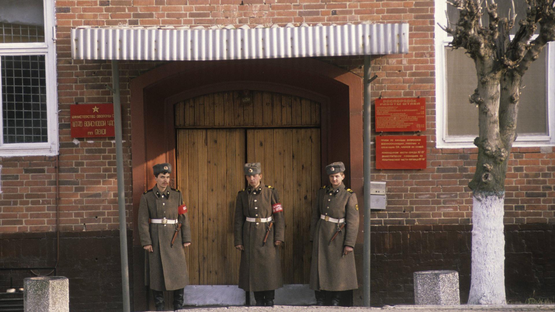 Drei Soldaten der Sowjetarmee stehen vor einem Eingangstor der Kaserne in Wünsdorf