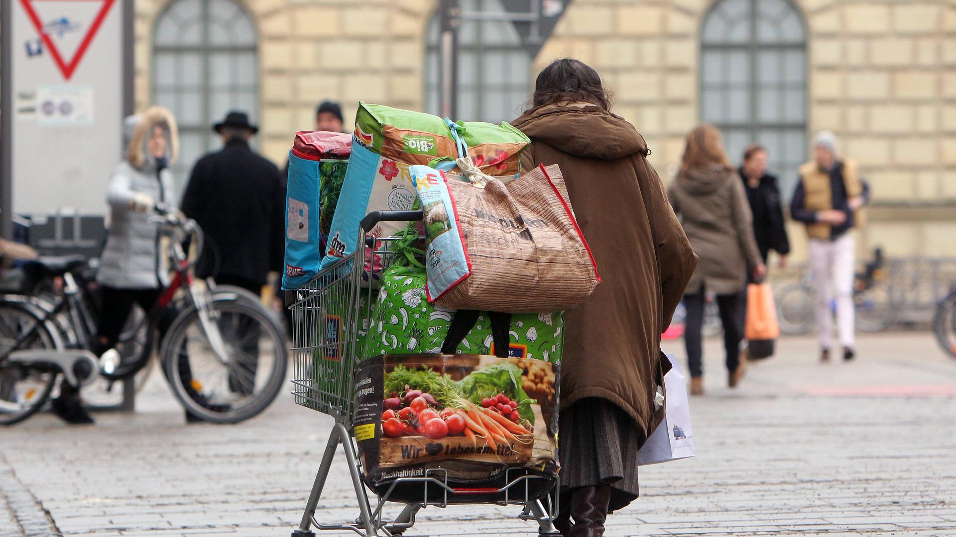 Obdachlose Frau transportiert ihr Hab und Gut in einem Einkaufswagen in der Innenstadt von München