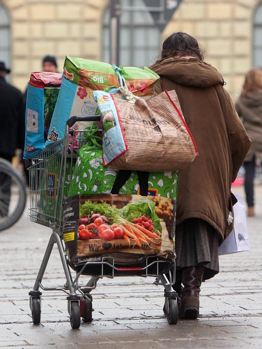 Obdachlose Frau transportiert ihr Hab und Gut in einem Einkaufswagen in der Innenstadt von München