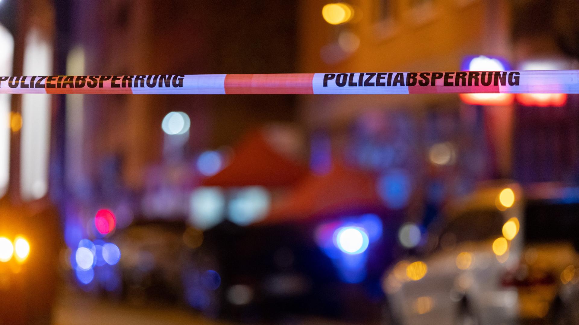 Ein Absperrband der Polizei hängt vor einem Tatort, nachdem hier Schüsse gefallen waren. Im Hintergrund stehen Polizisten neben einer Straßenbahn. Ein Absperrband der Polizei hängt vor einem Tatort, nachdem hier Schüsse gefallen waren. Im Hintergrund stehen Polizisten neben einer Straßenbahn.