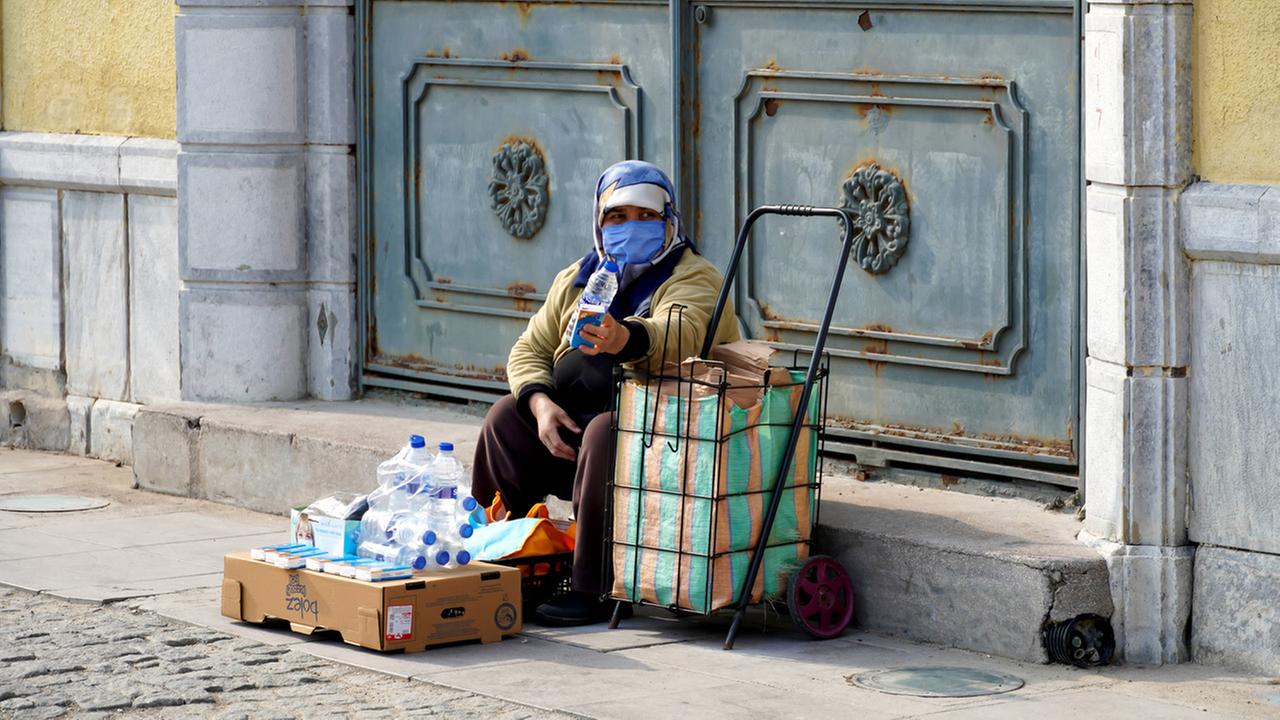 Eine Strassenverkäuferin in Alsancak, Izmir. Sie hat auf einer Pappkiste Plastikwasserflaschen und Taschentuchpackungen vor sich liegen.Türkei, 13. Februar 2022. Eine Strassenverkäuferin in Alsancak, Izmir. Sie hat auf einer Pappkiste Plastikwasserflaschen und Taschentuchpackungen vor sich liegen.Türkei, 13. Februar 2022.