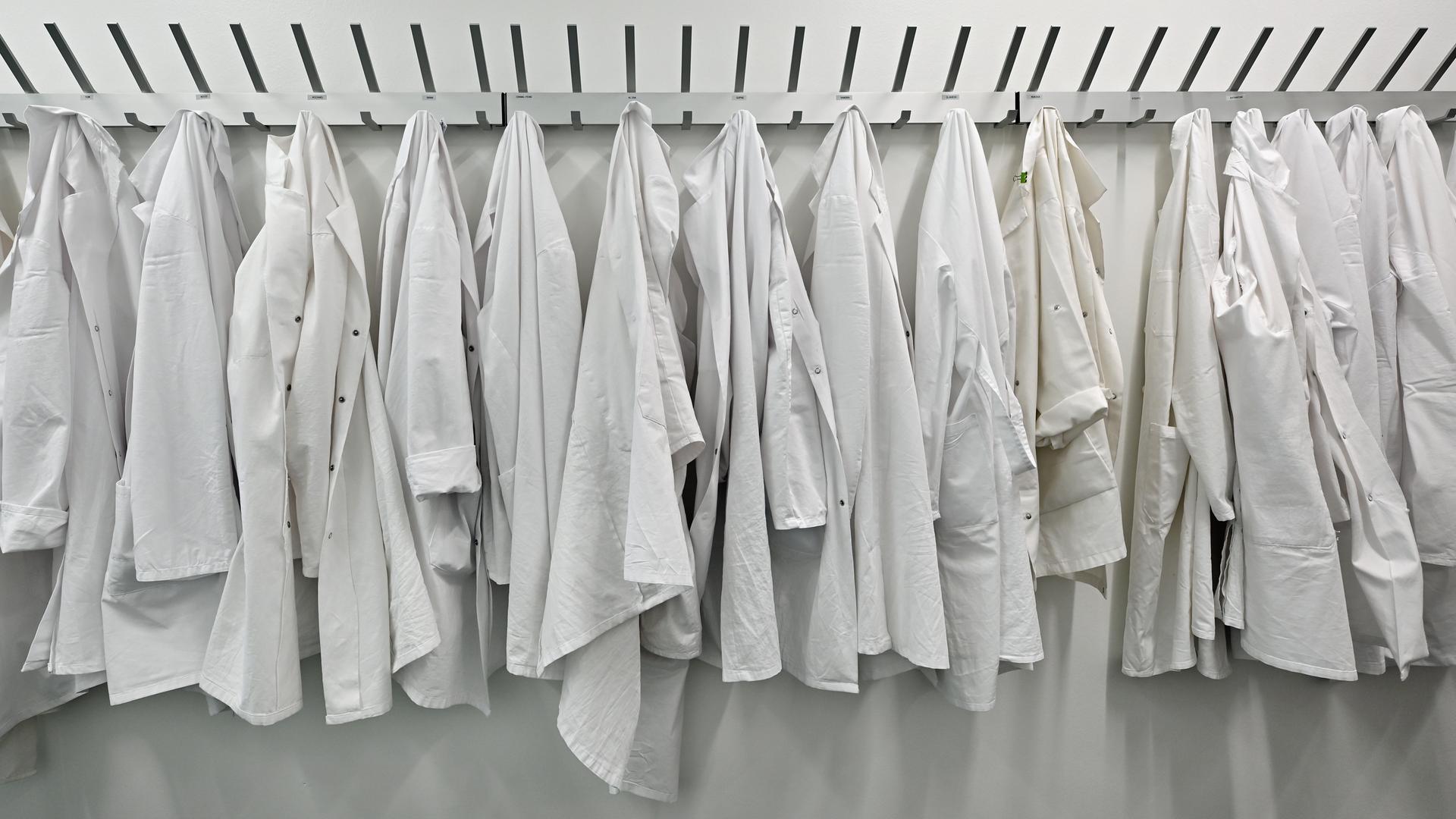 Laborkittel hängen im neuen Biotech-Center des Leibniz-Institut für Naturstoff-Forschung und Infektionsbiologie - Hans-Knöll-Institut nebeneinander an einer Garderobe. Laborkittel hängen im neuen Biotech-Center des Leibniz-Institut für Naturstoff-Forschung und Infektionsbiologie - Hans-Knöll-Institut nebeneinander an einer Garderobe.