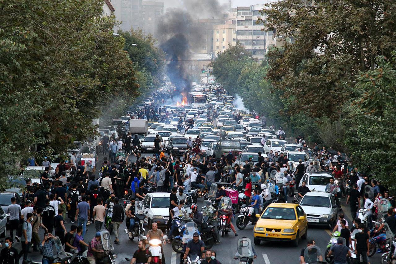 Demonstranten blockieren eine Straße in Teheran, Rachwolken sind zu sehen