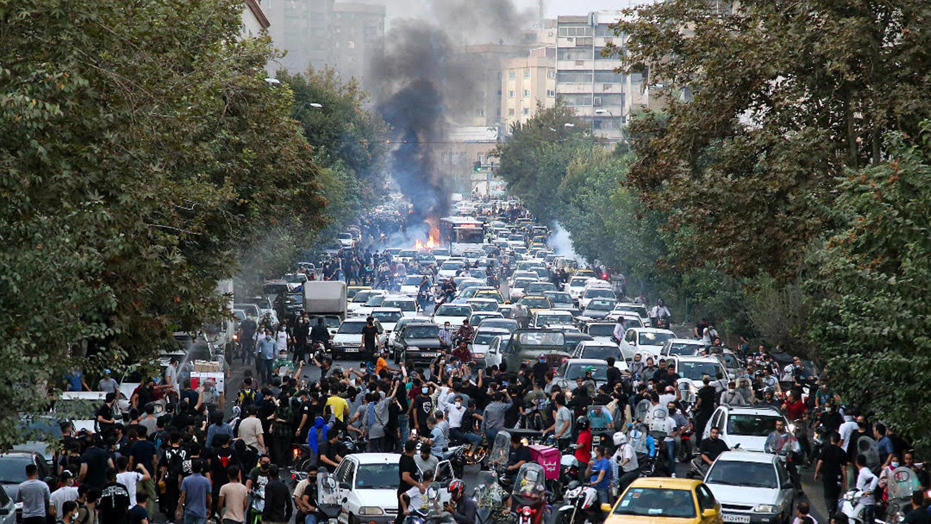 Demonstranten blockieren eine Straße in Teheran, Rachwolken sind zu sehen Demonstranten blockieren eine Straße in Teheran, Rachwolken sind zu sehen
