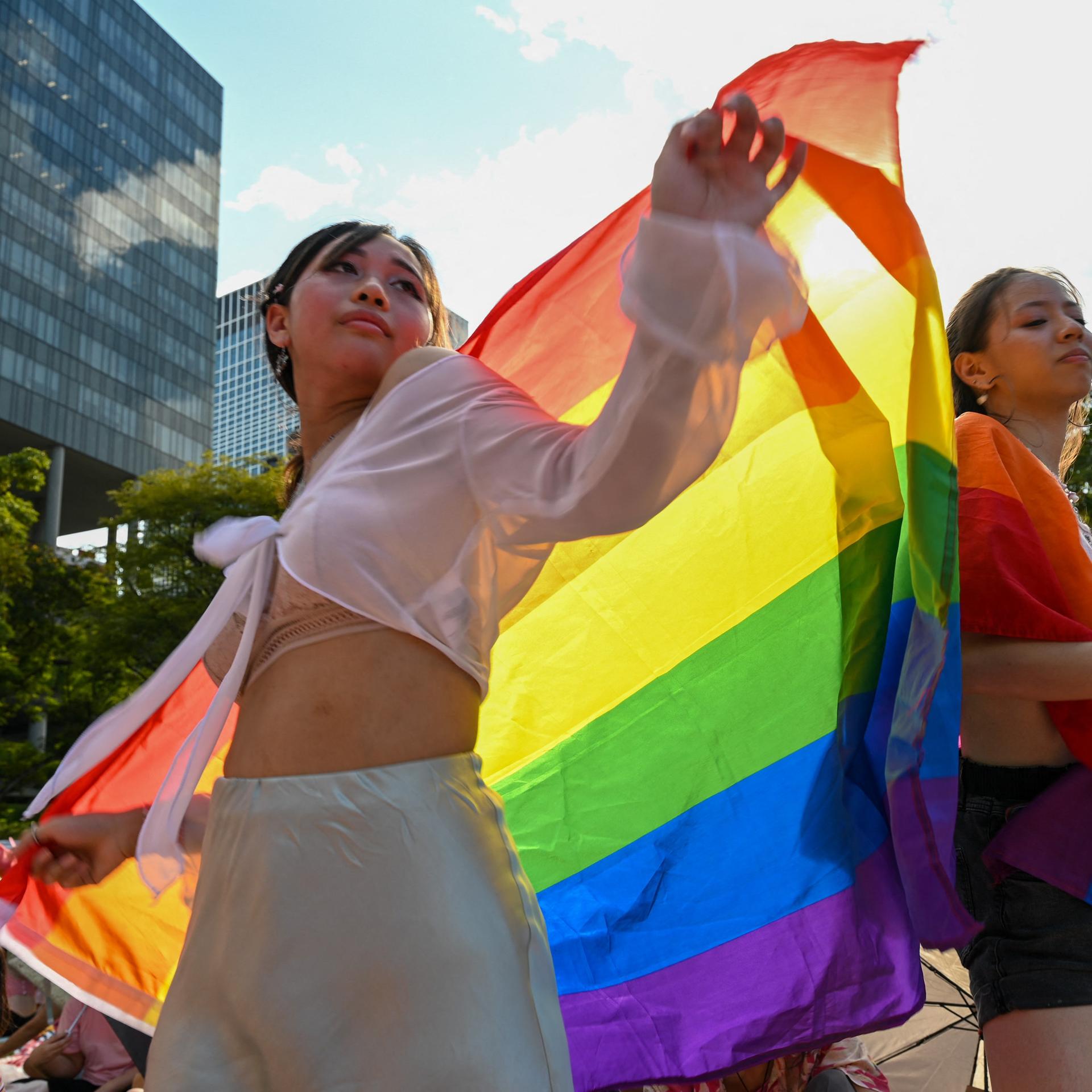 Zwei Frauen tanzen bei der "Pink Dot"-Veranstaltung in Singapur. Die Frau im Vordergrund trägte eine LGBTQ-Flagge als Umhang.
