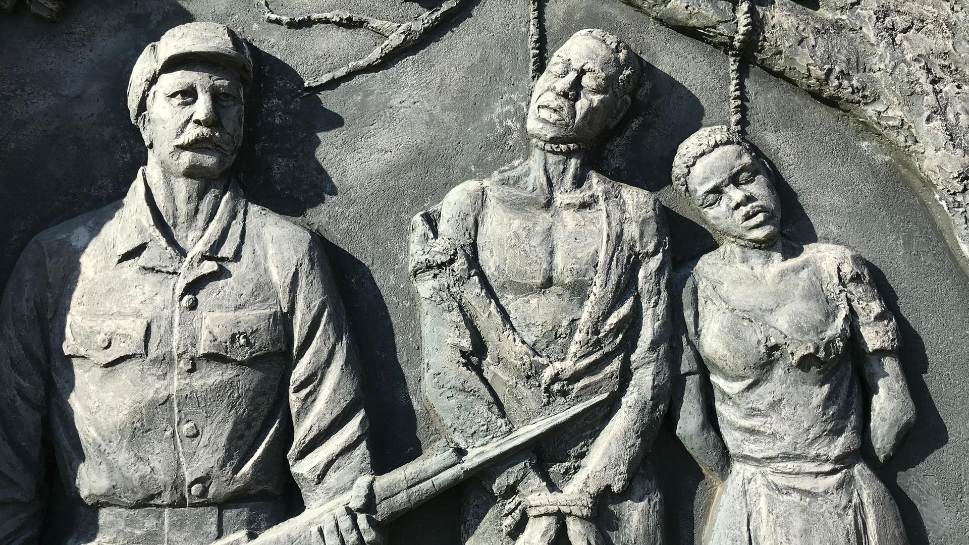 Ein Denkmal zur Erinnerung an den von deutschen Kolonialtruppen begangenen Völkermord an den Herero und Nama zeigt Gehängte neben einem schnauzbärtigen Soldaten. Ein Denkmal zur Erinnerung an den von deutschen Kolonialtruppen begangenen Völkermord an den Herero und Nama zeigt Gehängte neben einem schnauzbärtigen Soldaten.