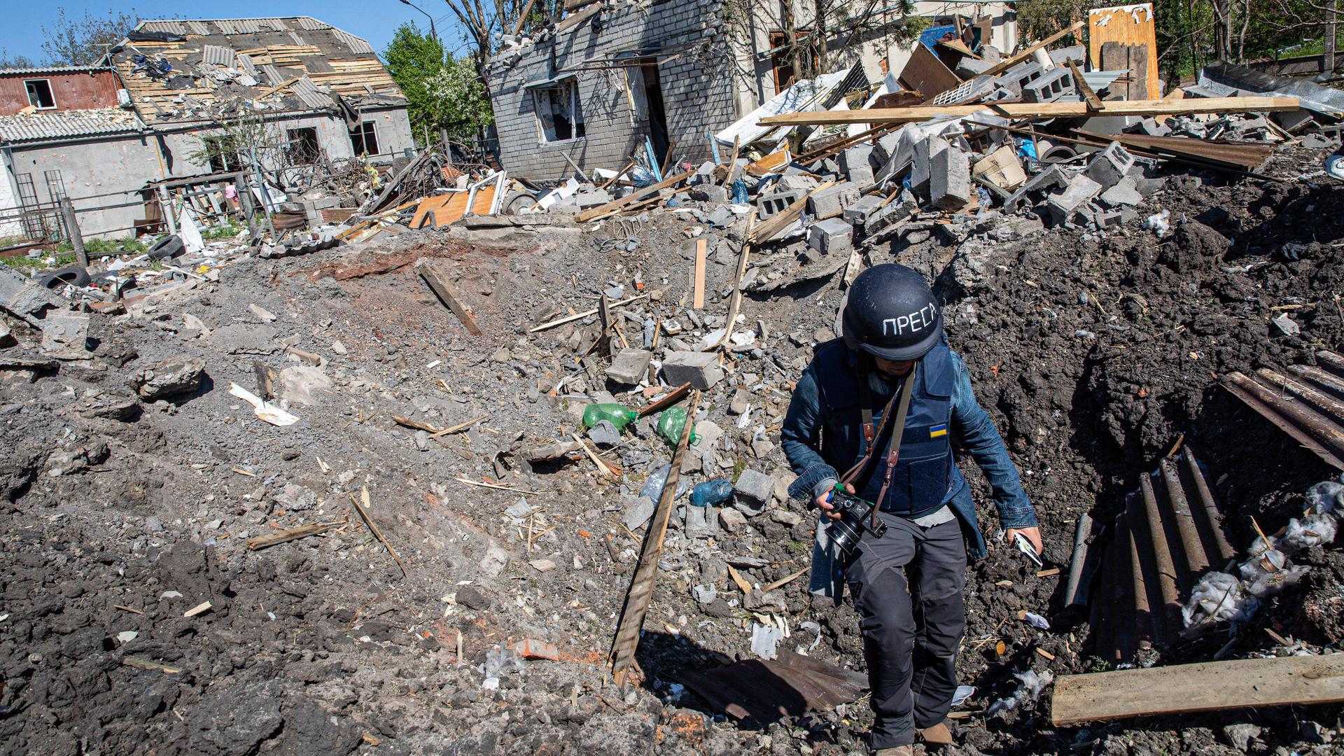 Ein Journalist steigt aus dem Krater einer Raketenexplosion in Slatyne in der Ukraine. Ein Journalist steigt aus dem Krater einer Raketenexplosion in Slatyne in der Ukraine.