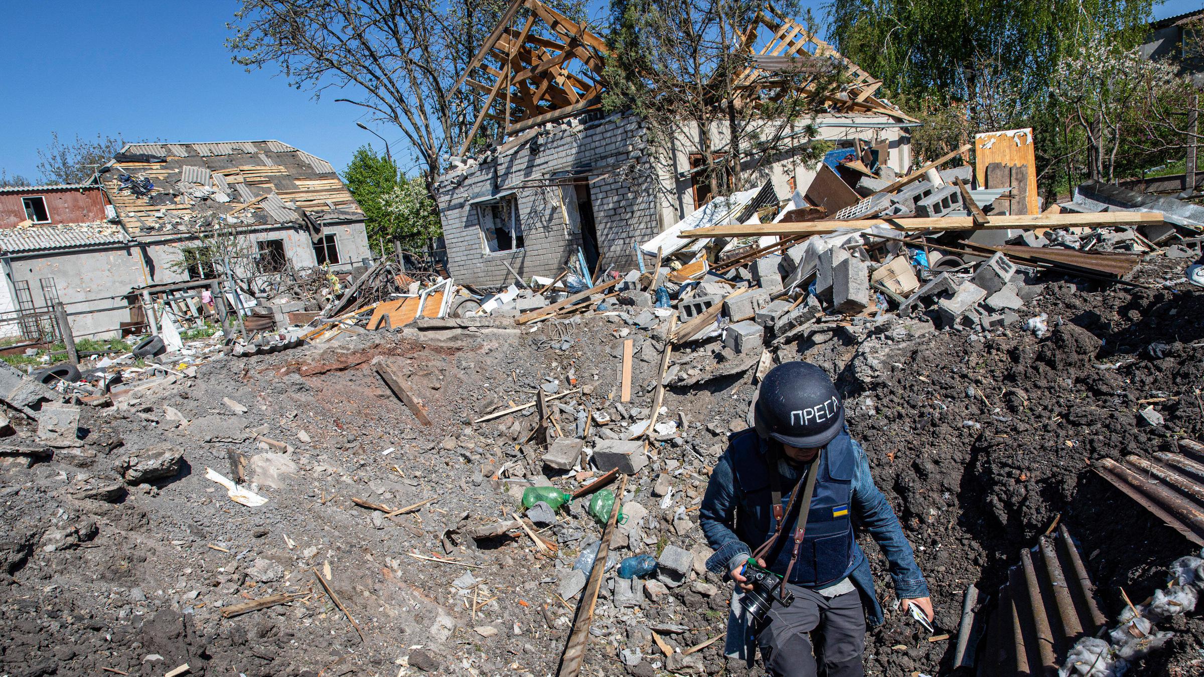 Ein Journalist steigt aus dem Krater einer Raketenexplosion in Slatyne in der Ukraine. 
