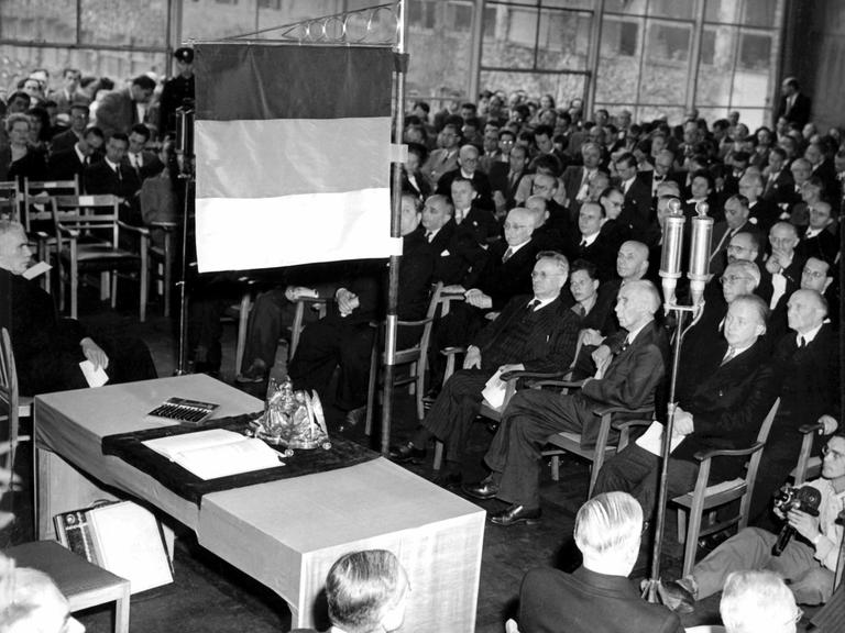 Unter einer schwarz-rot-goldenen Standarte liegt am 23.5.1949 das Grundgesetz der Bundesrepublik Deutschland auf einem Tisch im Sitzungssaal des Parlamentarischen Rates in Bonn. Das Gremium war an diesem Tag um 16.00 Uhr zu seiner letzten Sitzung zusammengetroffen. Während der Feierstunde unterzeichneten 68 Abgeordnete einschlieÃlich der Westberliner Vertreter das Grundgesetz der Bundesrepublik Deutschland. Der kommunistische Abgeordnete Heinz Renner und der KPD-Vorsitzende Max Reimann lehnten die Unterzeichnung ab. Zwei Wochen zuvor, am 8. Mai 1949, war das Grundgesetz vom Plenum des Parlamentarischen Rates mit 53 gegen zwölf Stimmen endgültig angenommen worden.