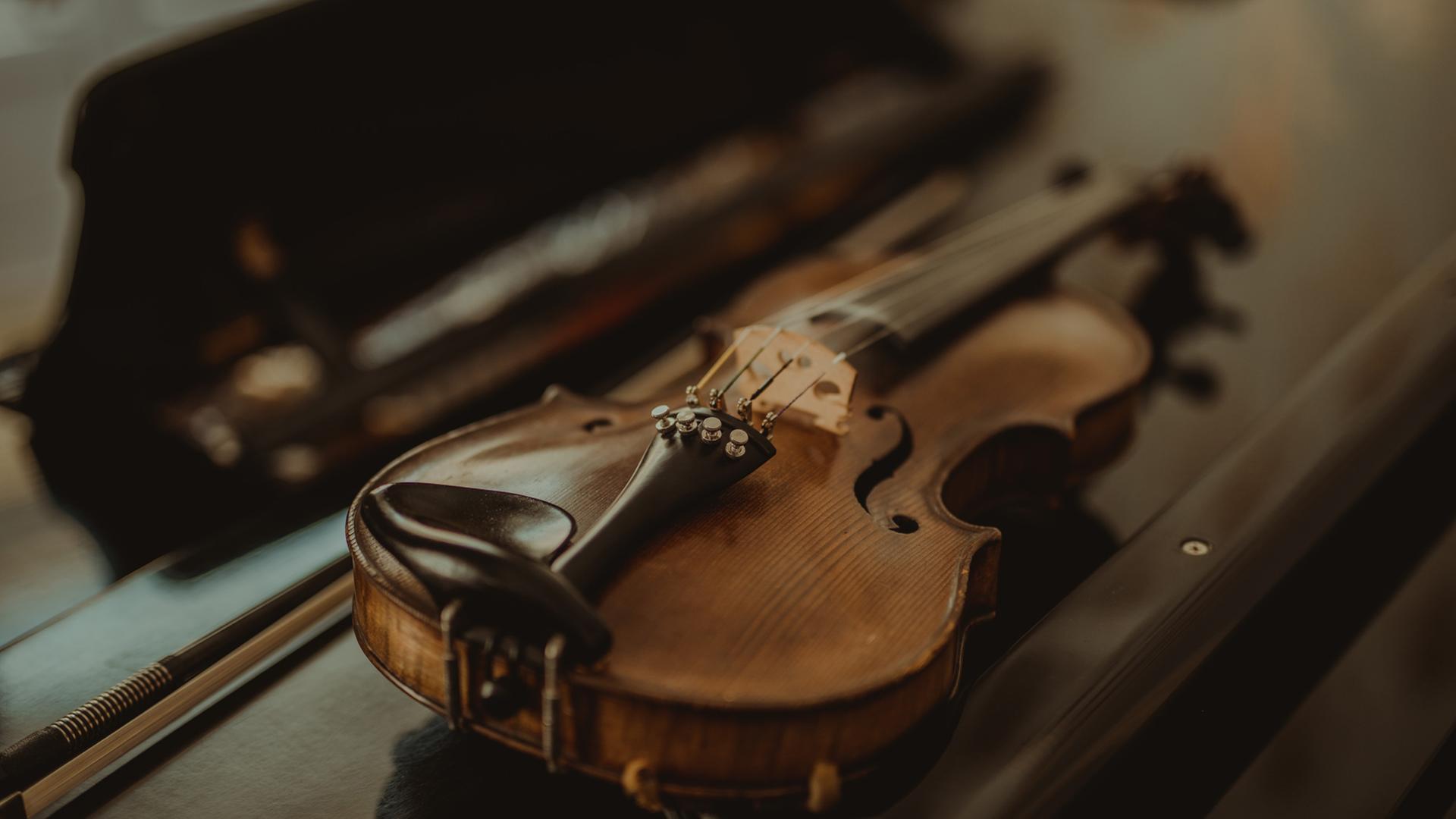 Wiederentdeckte Instrumente werden zu neuem musikalischen Leben erweckt. Zu sehen: Eine kleine Geige liegt auf einem Tisch, dahinter der geöffbete Geigenkasten. Wiederentdeckte Instrumente werden zu neuem musikalischen Leben erweckt. Zu sehen: Eine kleine Geige liegt auf einem Tisch, dahinter der geöffbete Geigenkasten.
