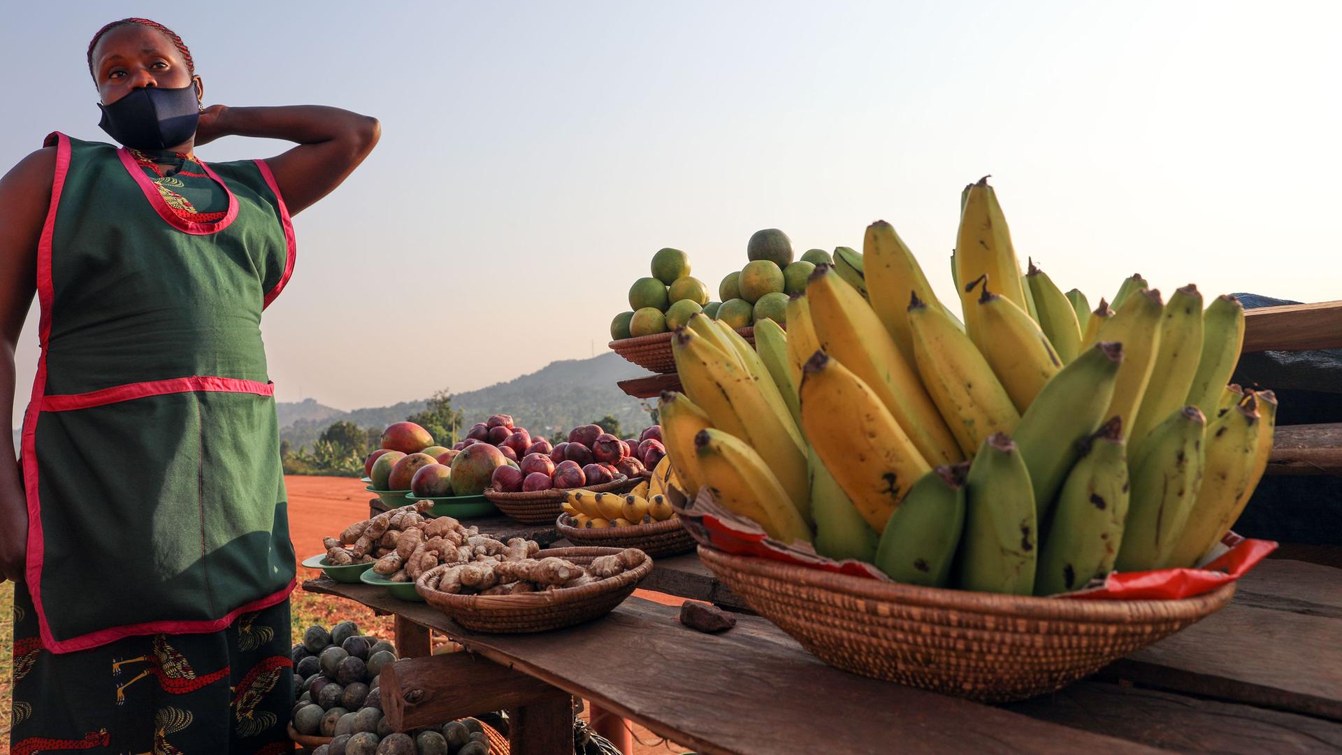 Eine Frau steht an einem Korb mit Obst in Kampala, Uganda. Eine Frau steht an einem Korb mit Obst in Kampala, Uganda.