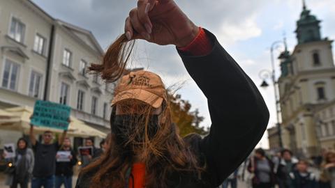 Eine Frau hält bei einer Demonstration eine abgeschnittene Haarsträhne hoch.