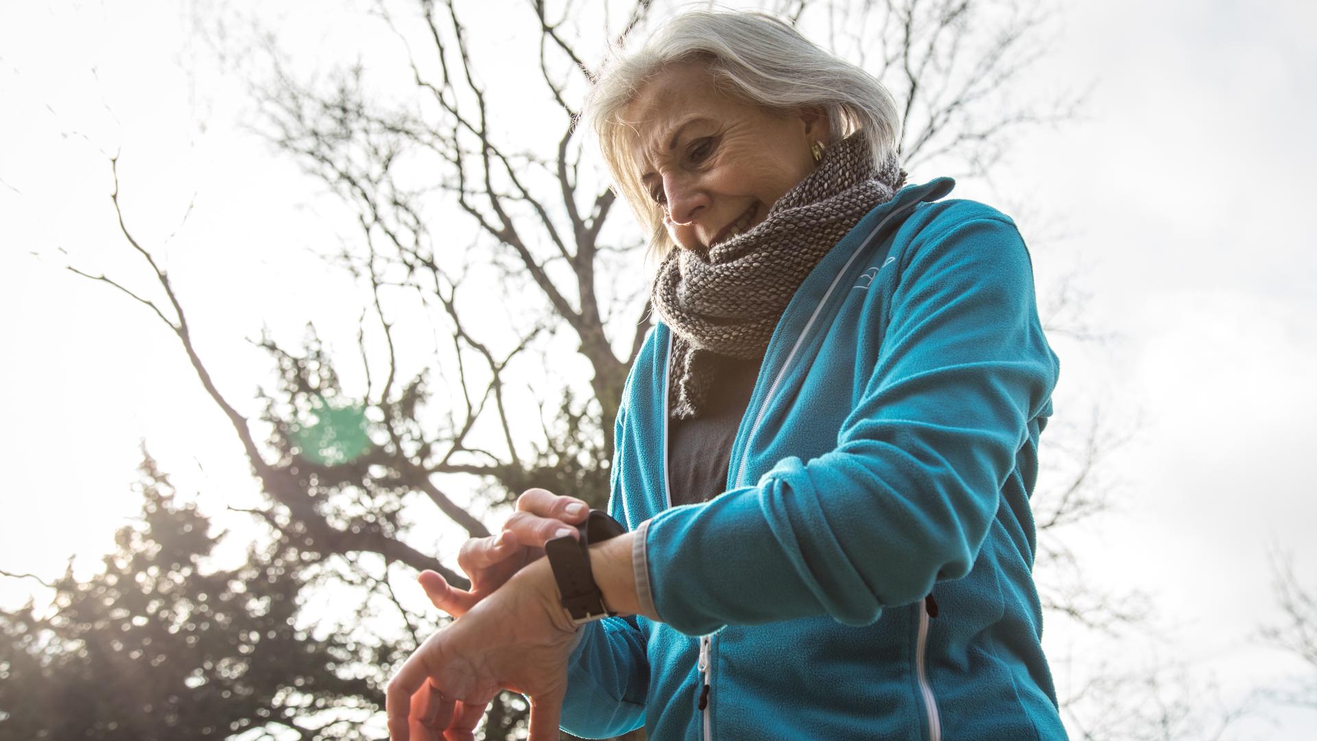Eine ältere Joggerin in einem Park in Hamburg schaut auf ihr Wearable. (Symbolbild)