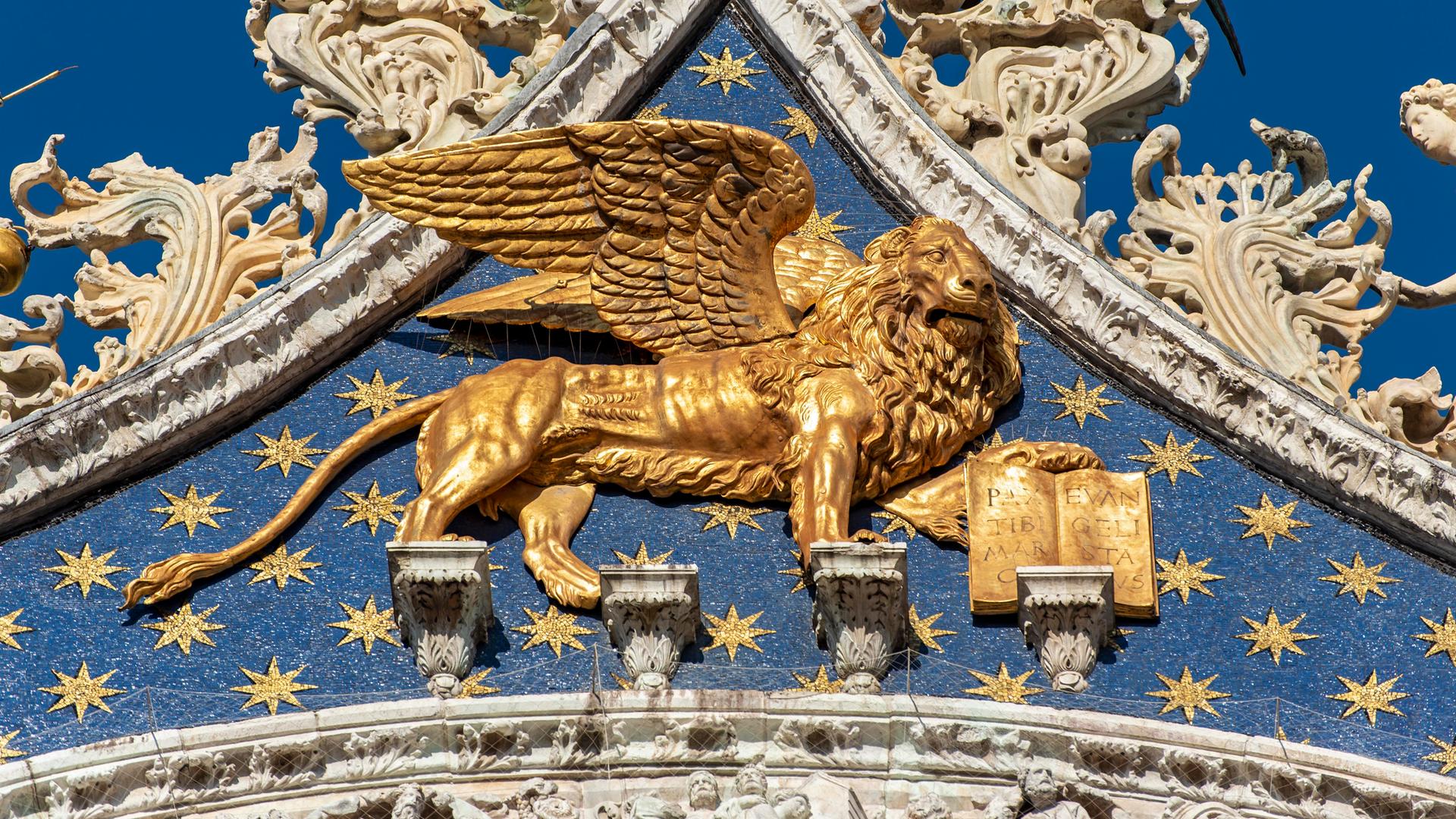 Ein goldener geflügelter Löwe am Markusdom in Venedig Ein goldener geflügelter Löwe am Markusdom in Venedig