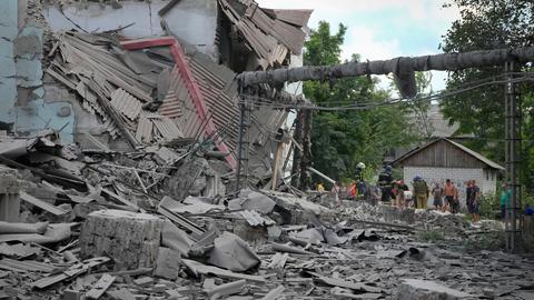 Ukraine, Lyssytschansk: Rettungskräfte und Anwohner bergen nach einem russischen Luftangriff eine Leiche aus den Trümmern eines Gebäudes.