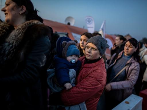 Frauen aus der Ukraine mit ihren Kindern warten kurz hinter der Grenze zur Ukraine, darauf, von Helfern in Empfang genommen zu werden.