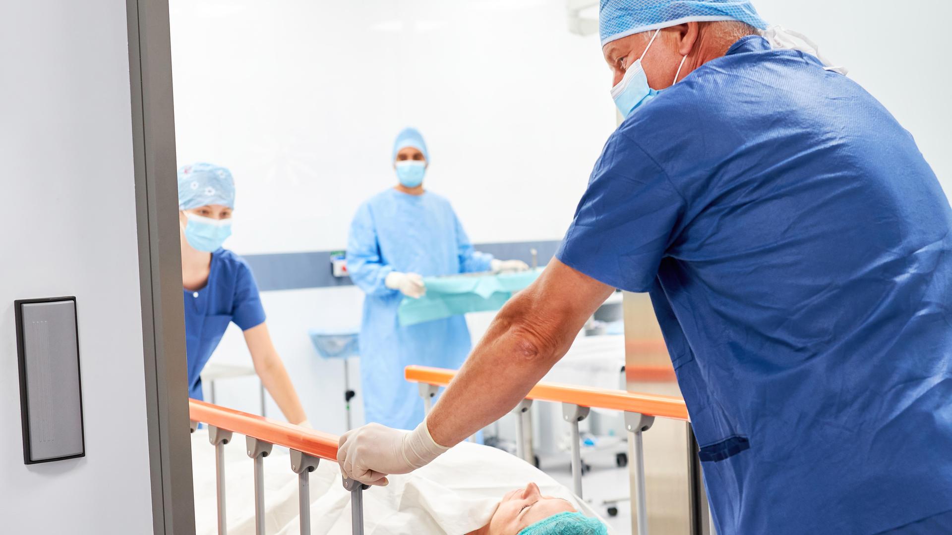 Zwei Pflegekräfte schieben Patient im Krankenbett Zwei Pflegekräfte schieben Patient im Krankenbett