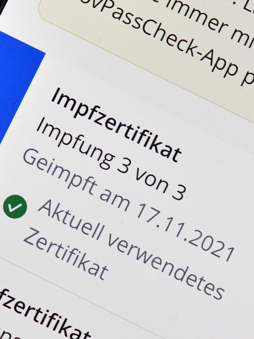Symbolfoto App CovPass auf Smartphone mit digitalem europäischen Impfzertifikat nach dritter erfolgter Booster-Impfung gegen Covid-19