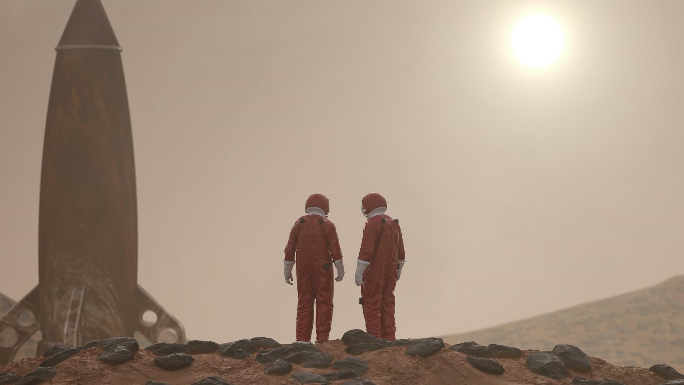 Zwei Personen in roten Ganzkörperanzügen auf rotem, steinigen Untergrund. Neben ihnen eine Rakete, aufrecht stehend. Am Horizont die Sonne. Zwei Personen in roten Ganzkörperanzügen auf rotem, steinigen Untergrund. Neben ihnen eine Rakete, aufrecht stehend. Am Horizont die Sonne.