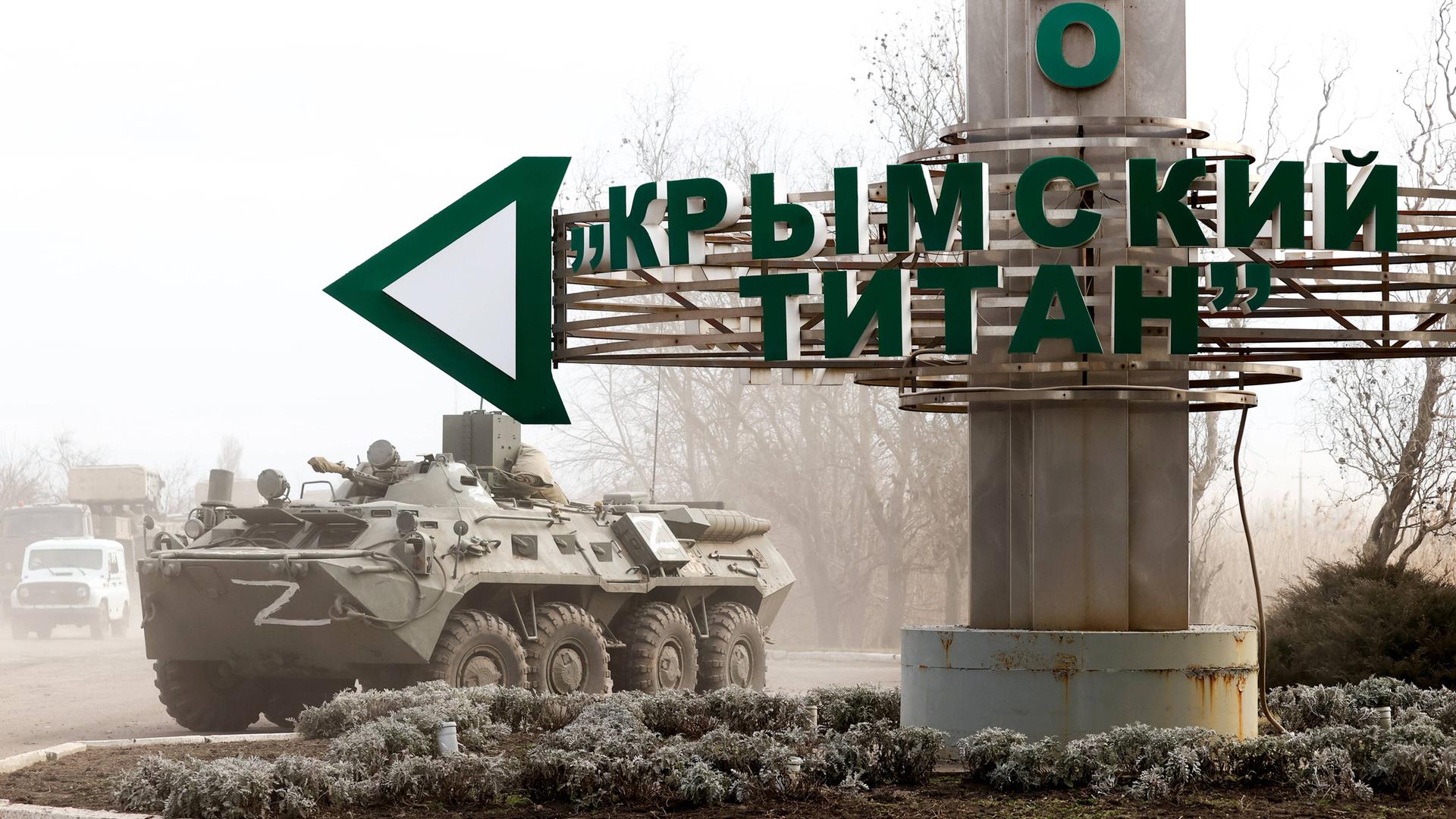 Ein Straßenschild bei dem Checkpoint Perekop an der ukrainischen Grenze weist den Weg zu der Titan-Anlage in Armyansk auf der Krim, neben dem Schild ein Panzer.