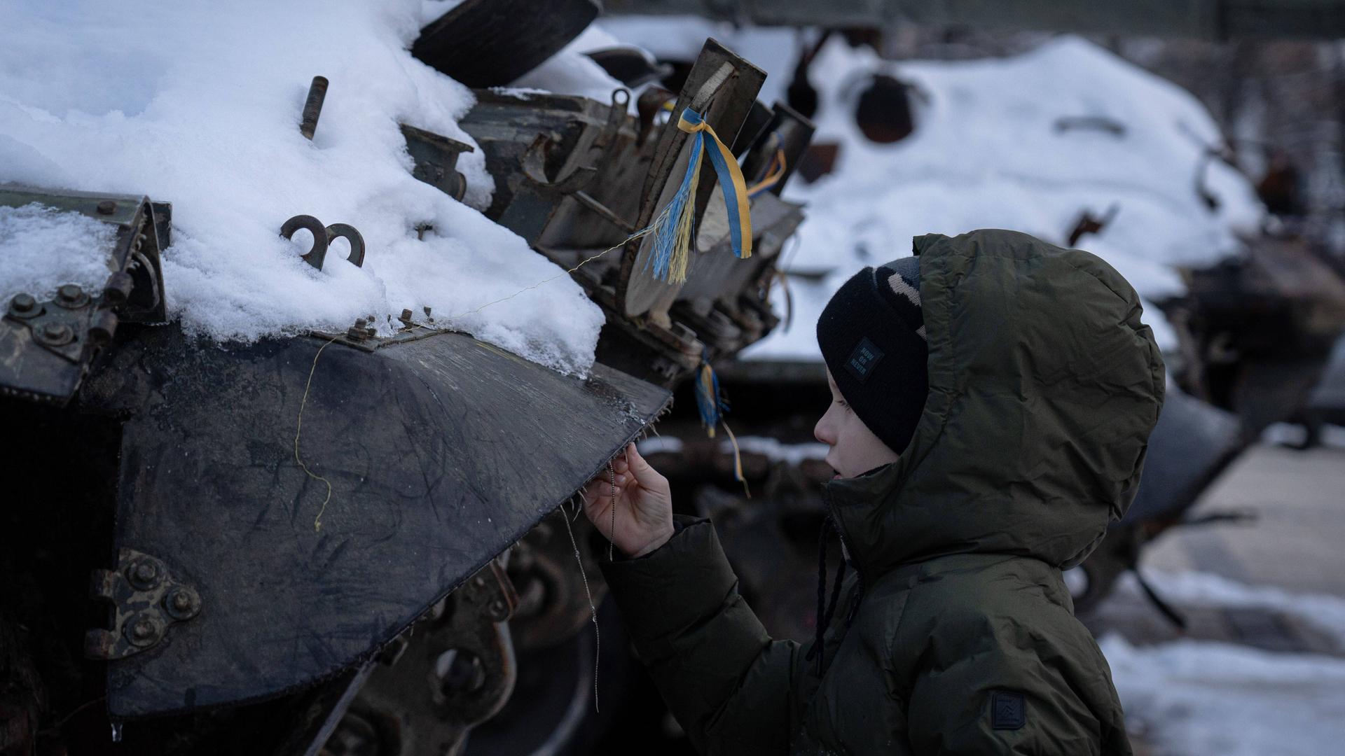 Kiew, Ukraine: Ein Junge steht im Winter neben einem zerstörten Fahrzeug der russischen Armee.
Kiew, Ukraine: Ein Junge steht im Winter neben einem zerstörten Fahrzeug der russischen Armee.