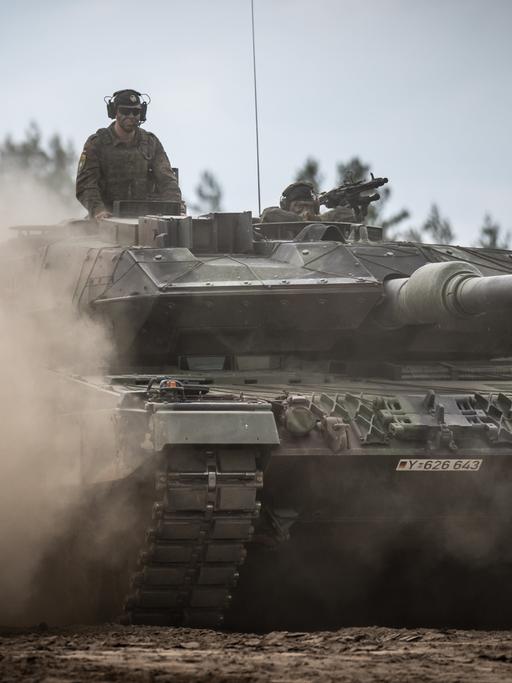 Aus einem fahrenden Leopard-2-Panzer schaut ein Soldat.