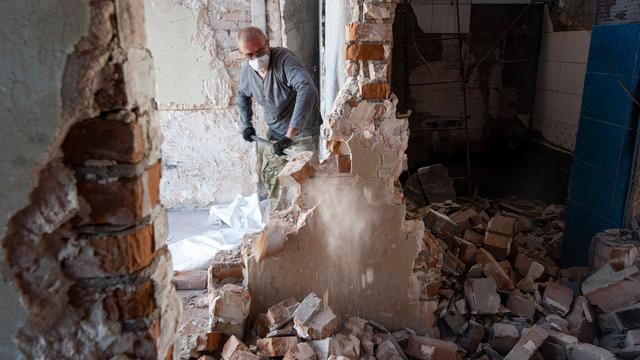Ein Mann versucht in einem Haus mit einer Schaufel die Schäden zu beseitigen.