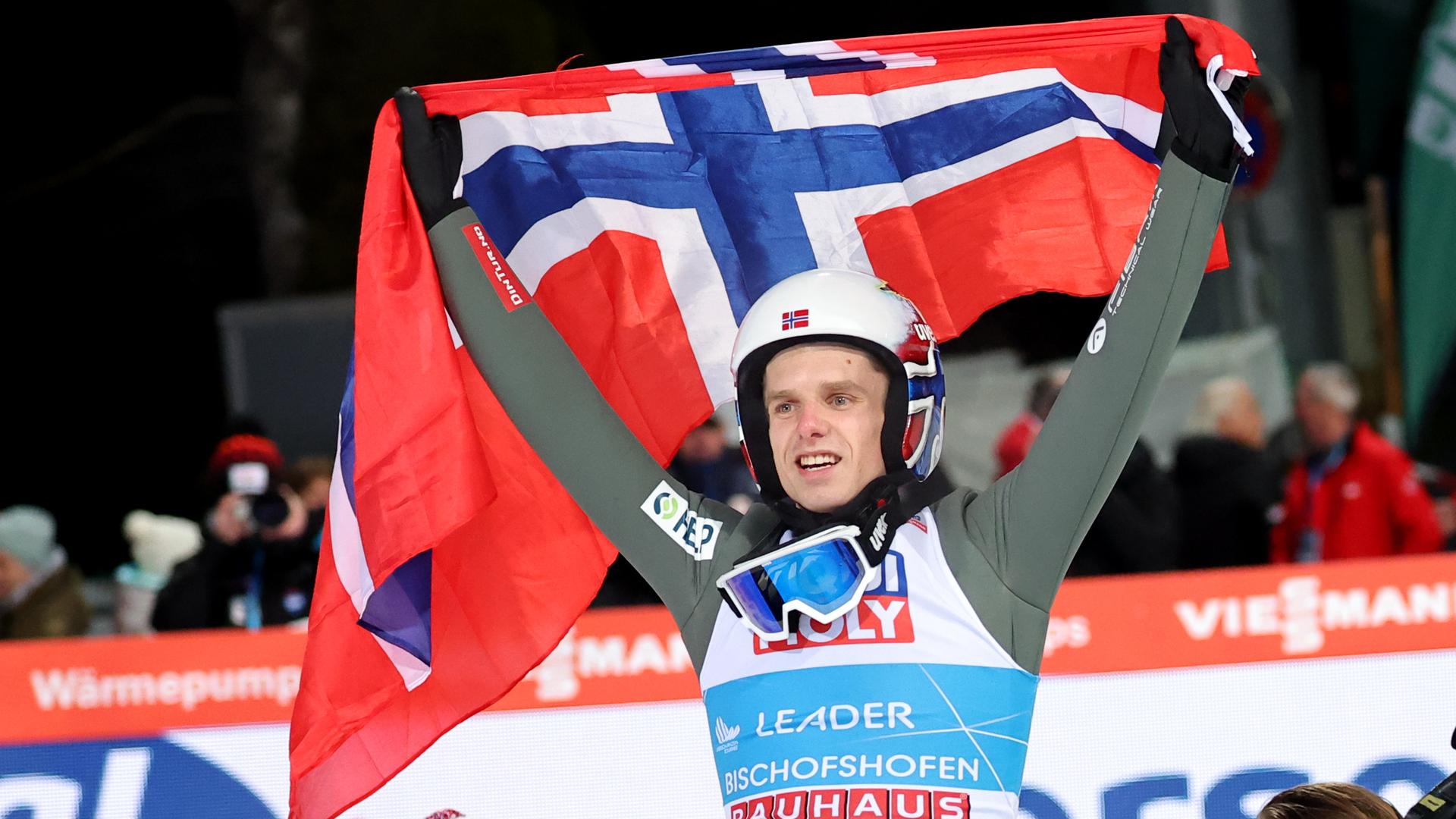 Halvor Egner Granerud aus dem Land Norwegen jubelt. Er hält eine norwegische Flagge über seinem Kopf.