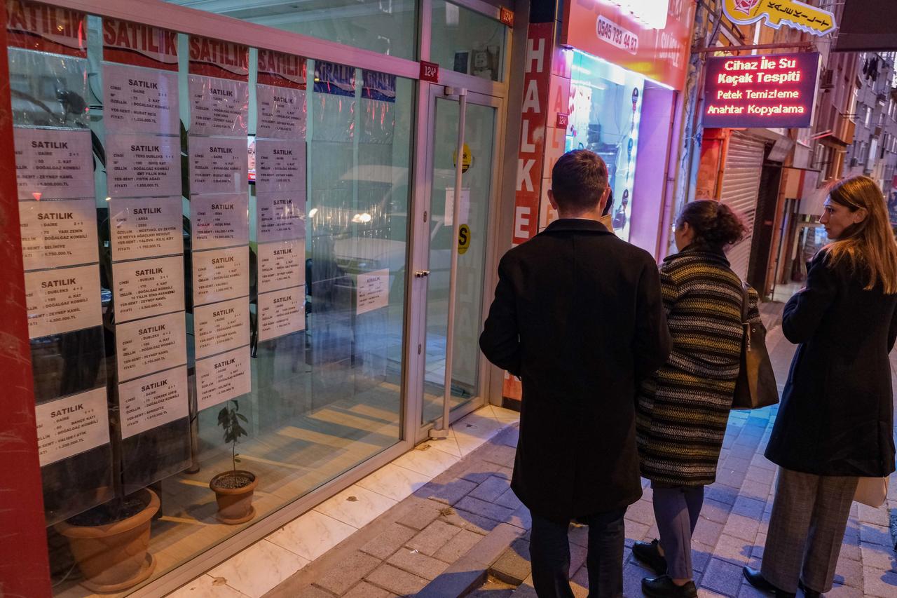 Passanten vor einem Laden mit kleinen bedruckten Zetteln im Fenster.
