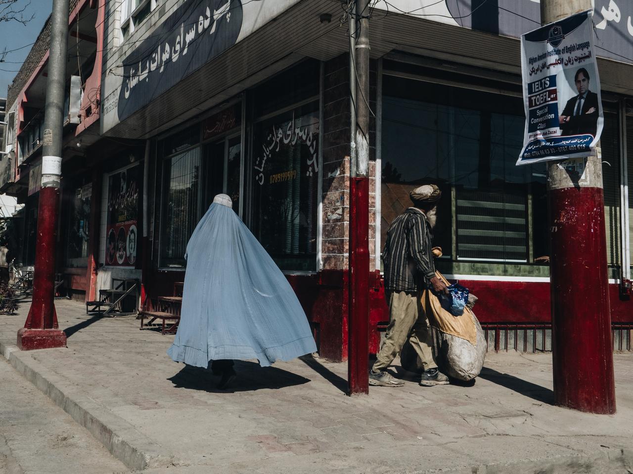 Straßenszene in Kabul: Eine vollverschleierte Frau und ein Mann gehen die Straße entlang. Straßenszene in Kabul: Eine vollverschleierte Frau und ein Mann gehen die Straße entlang.