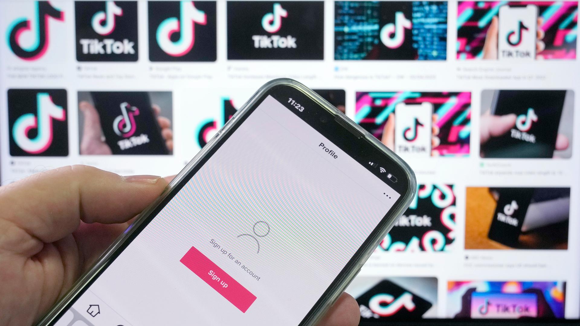 TikTok-App auf einem Smartphone vor Werbe-Screens in Sydney, Australien TikTok-App auf einem Smartphone vor Werbe-Screens in Sydney, Australien